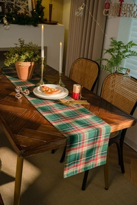 Close-up of a festive red and green plaid table runner on a Christmas decorated dining table