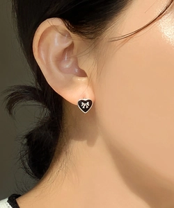 Close-up of a 925 silver black heart earring with a bow motif worn on a model ear
