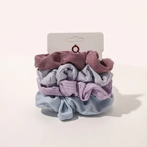 Close-up of four ribbed fabric scrunchies in Morandi colors with paper display card