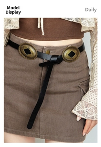 Detail of vintage black belt with large oval brass conchos on brown corduroy skirt