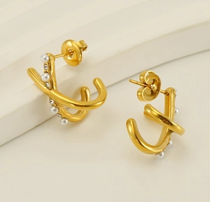 Detail of gold crossover hoop earrings with inlaid white pearls and sparkling crystals