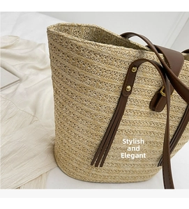 Detail of straw tote bag featuring brown leather handles and decorative metal rivets