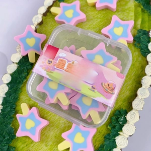 Detail of star-shaped lollipop erasers in a transparent box on a green background