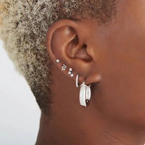 Macro shot of 925 sterling silver ear piercing set featuring snake stud and crystal hoop