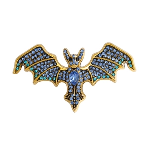 Vintage bat brooch with gold plating and blue gradient rhinestones on white background