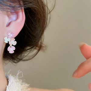 Detail close-up of pink enamel flower stud earrings worn on ear, sweet floral jewelry.