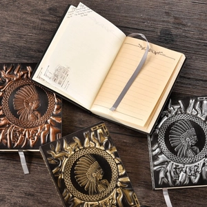 Vintage embossed A5 notebook in bronze, gold, and silver finishes on a dark wood background