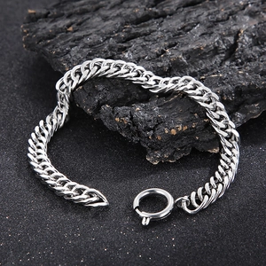 Detailed view of silver titanium steel Cuban link bracelet with spring clasp on textured base
