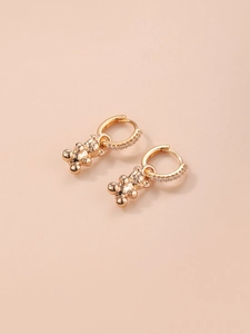 Golden bear dangle earrings with sparkling rhinestones on a soft pink background