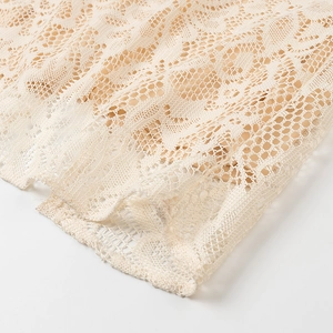 Macro della texture in pizzo beige e intricati motivi traforati sull'orlo del vestito