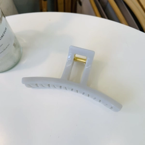 Detail view of a large matte grey hair claw clip with a strong golden metal spring