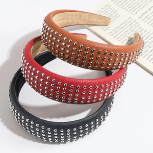 Studded faux leather wide headbands in brown, red, and black on a book background