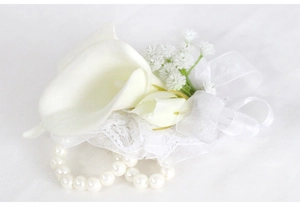 Detailed view of bridal wrist corsage with white calla lilies and pearl bracelet