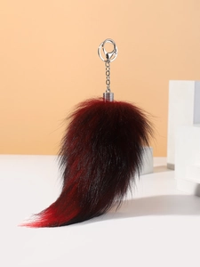 Macro shot of fluffy red and black gradient fur fox tail pendant with silver metal clasp