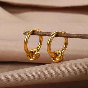 Minimalist gold hoop earrings featuring triple ring pendants on elegant rustic wood display