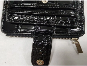 Detailed close-up of black crocodile pattern leather wallet with snap and metal zipper