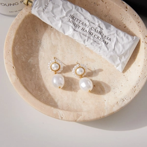 Macro view of gold flower earrings with white pearls on a natural stone tray