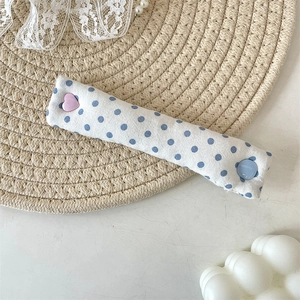 Detailed view of polka dot cable organizer strap with pink heart and blue round button