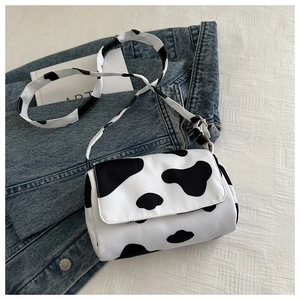 Close-up of cow print canvas crossbody bag placed on blue denim jacket