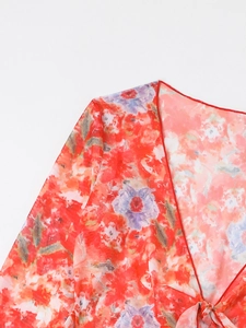Detail of red floral mesh cover-up featuring V-neckline and delicate front tie-knot closure