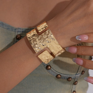 Detail of gold-plated wide cuff bracelet with irregular hammered texture and cutouts
