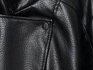 Detail of premium black faux leather texture with fine stitching and silver metal button