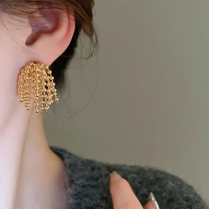 Close-up of gold beaded tassel earrings showing layered chains and elegant metallic texture