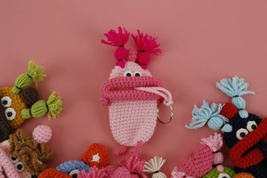 Macro shot of handmade crochet monster key cover with pink yarn tassels and metal ring