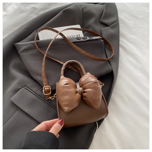 Detail of a brown PU leather crossbody bag with a large stylish stuffed bow decoration