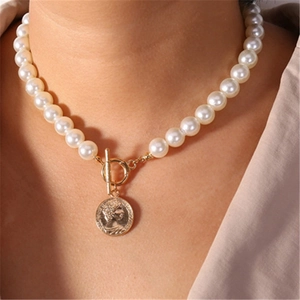 Chic faux pearl necklace with a vintage golden portrait coin pendant on a female model