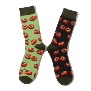 Detail view of red tomato patterns on green and black crew socks with fine knit texture