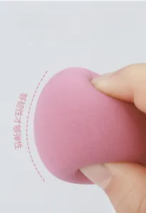 Macro shot of flexible pink makeup sponge being squeezed to show soft rebound texture