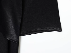 Vue détaillée du tissu satiné noir montrant la texture lisse et les coutures précises