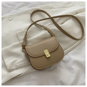 Detail of khaki saddle bag with golden metal buckle clasp on white fabric surface
