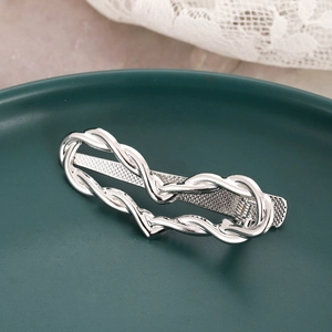 Minimalist silver wavy metal hair clip with a heart-shaped twist on dark ceramic plate