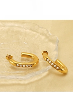 Detail of U-shaped gold earrings with 18K plating and white pearls on silk