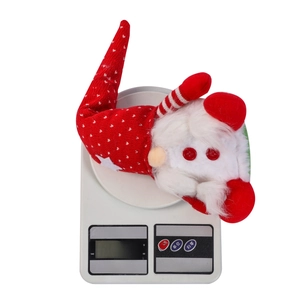 Close-up of a Christmas gnome plush with a red heart hat weighing 123g on a scale