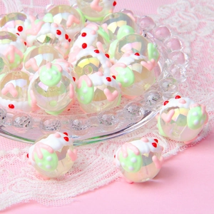 Macro shot of hand-painted acrylic strawberry beads with cream glue details in a glass dish