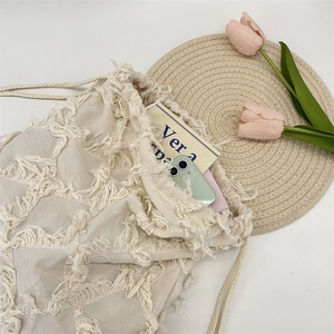 Detail view of cream canvas tote bag with fringe texture and drawstring closure