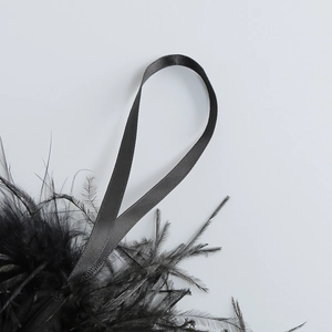 Détail de plumes d'autruche noires avec ruban de satin gris pour robe de soirée