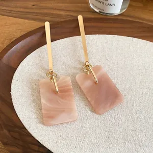 Elegant rectangular marble-texture resin earrings with long gold needles on white cloth
