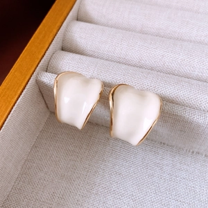 Detail view of cream C-shape hoop earrings with gold trim in a beige jewelry box