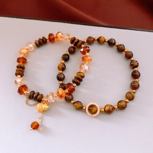 Détail du bracelet en perles d'oeil de tigre avec pendentif gourde dorée et glands