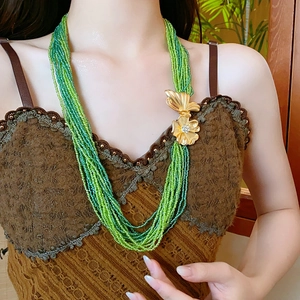Detailed view of multilayered green beaded necklace with gold crystal floral clasp