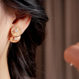 Detailed close-up of a gold-plated pearl and zircon earring on model's ear