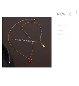 Detailed macro view of heart pendant necklace with red zircon and gold-plated chain links