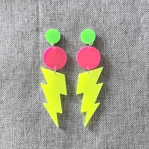 Detailed shot of neon acrylic lightning bolt earrings in fluorescent green and pink