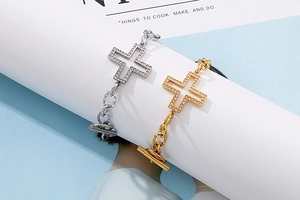 Detail view of gold and silver cross charm bracelets with zircon and toggle clasp