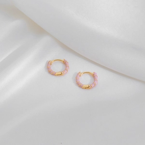 Detailed macro of pink enamel and gold-plated twisted geometric hoop earrings
