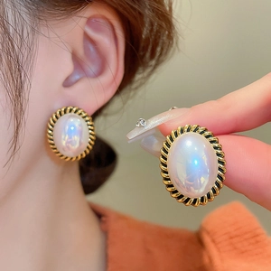 Détails macro de boucles d'oreilles baroques avec perles ovales et bordure dorée torsadée